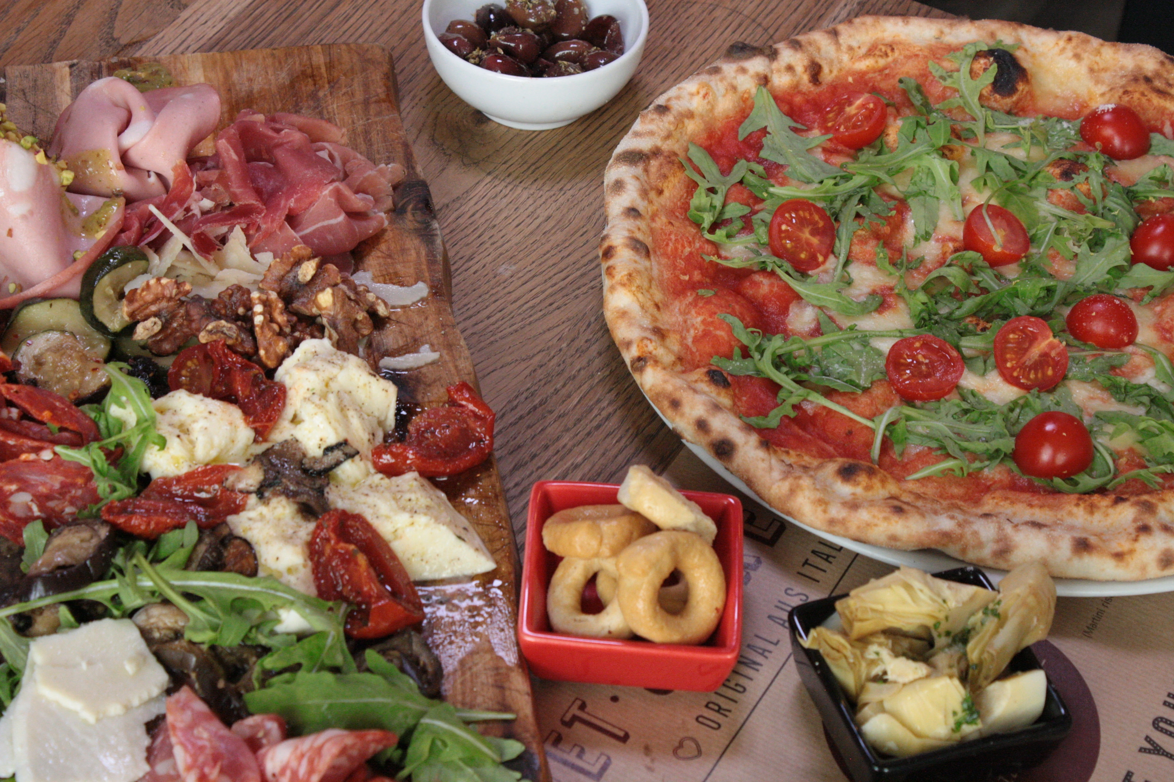 Italienische Köstlichkeiten: Pizza, Aufschnittplatte, Oliven und Taralli